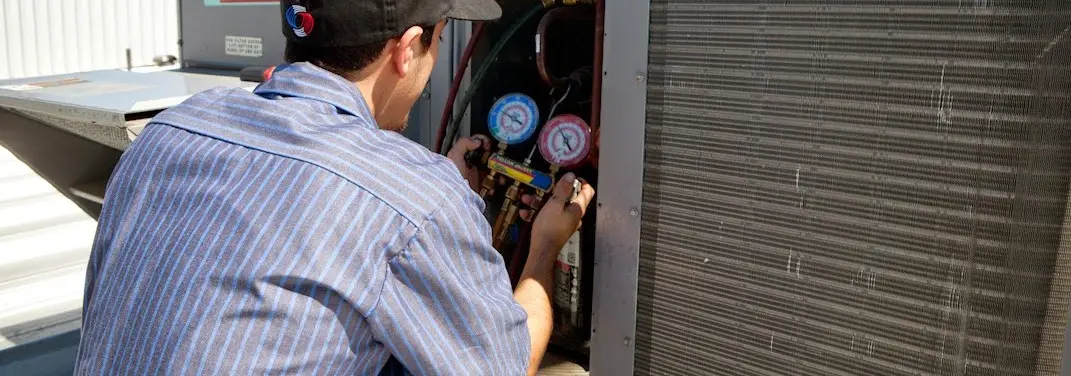 HVAC technician servicing a condenser unit in New Sewickley